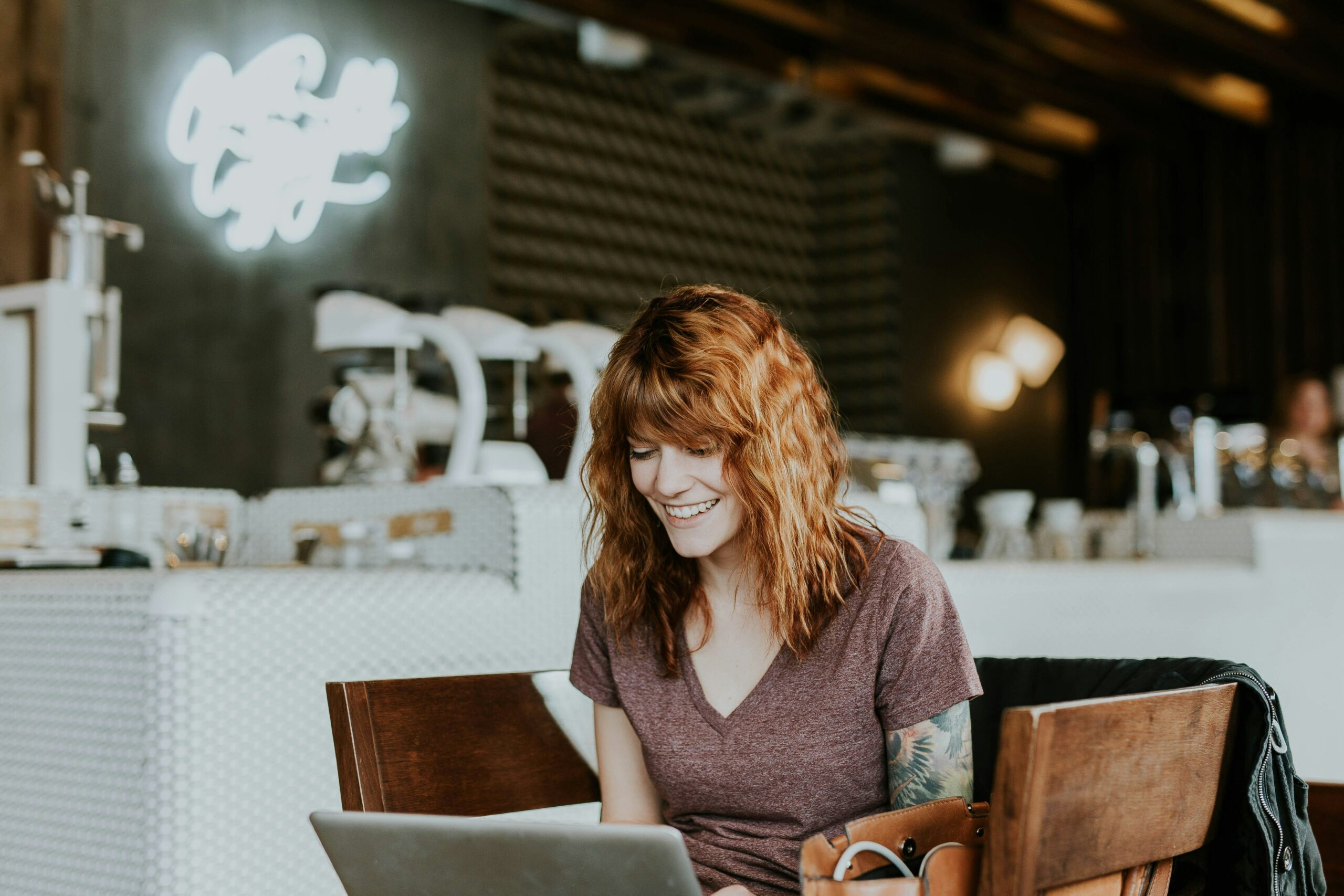 Woman sitting on brown wooden chair while using silver laptop computer in bedroom