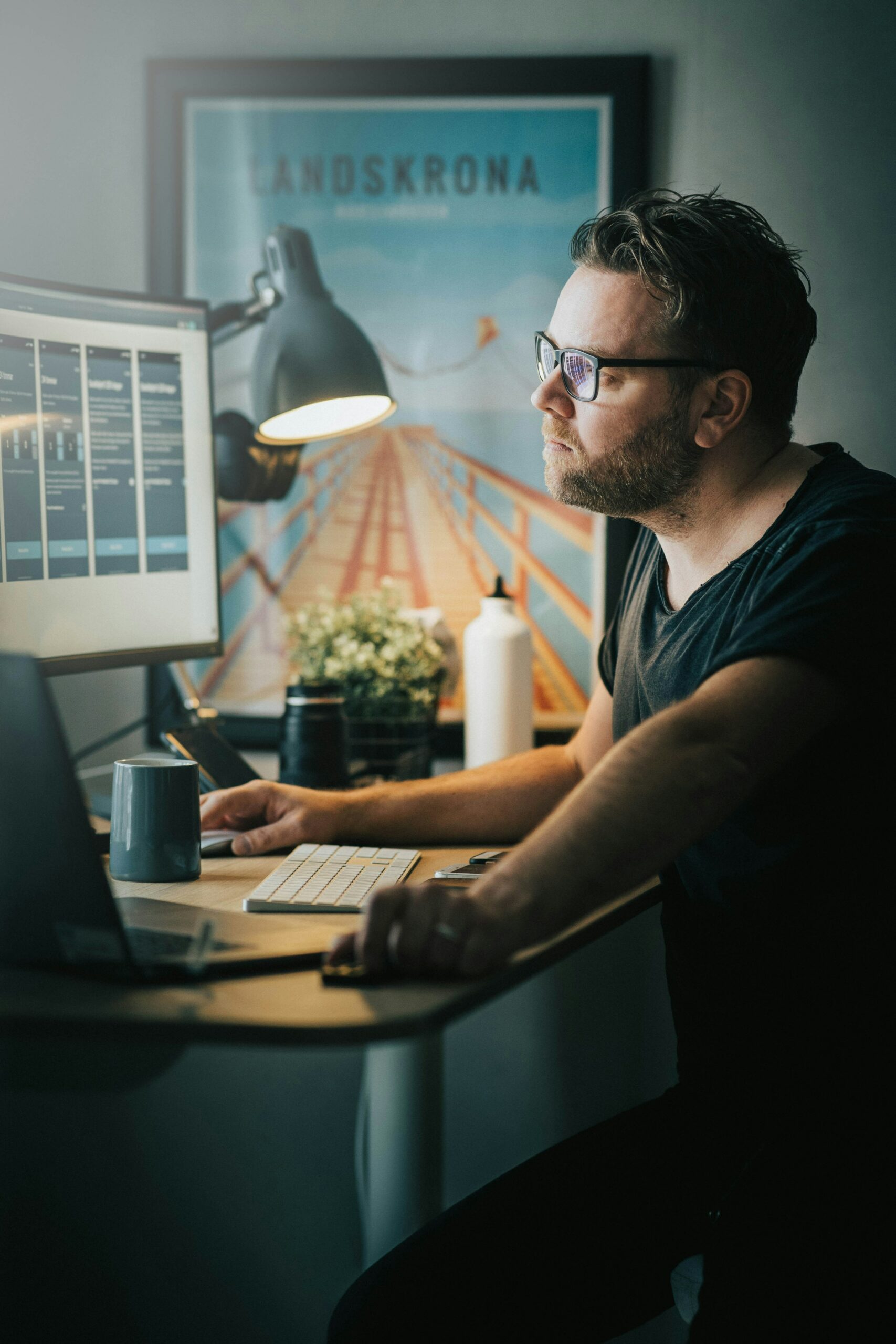 Man with a black tshirt and black glasses using the computer