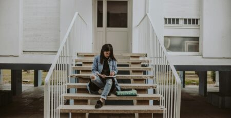 woman sitting on stairs while holding book