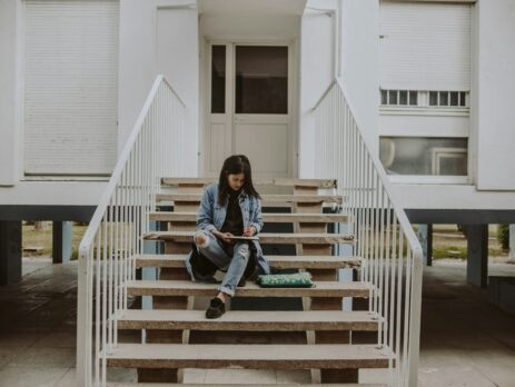 woman sitting on stairs while holding book