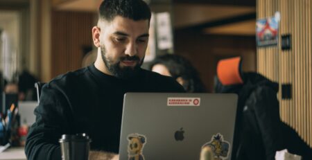 Man in a black shirt using a laptop macbook