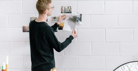 man holding a paper in front of a wall