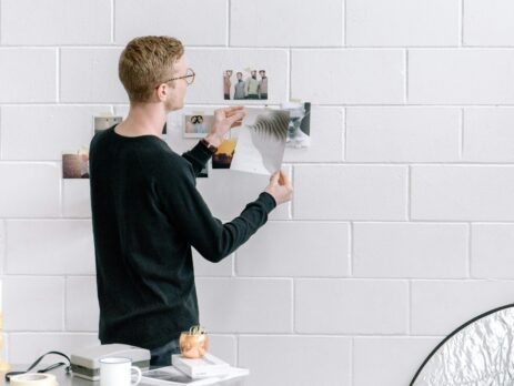 man holding a paper in front of a wall