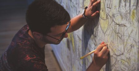 person holding a pen writing on a wall