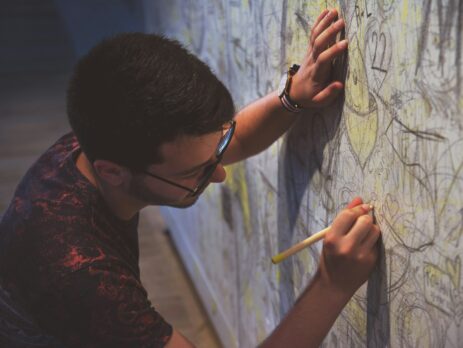 person holding a pen writing on a wall