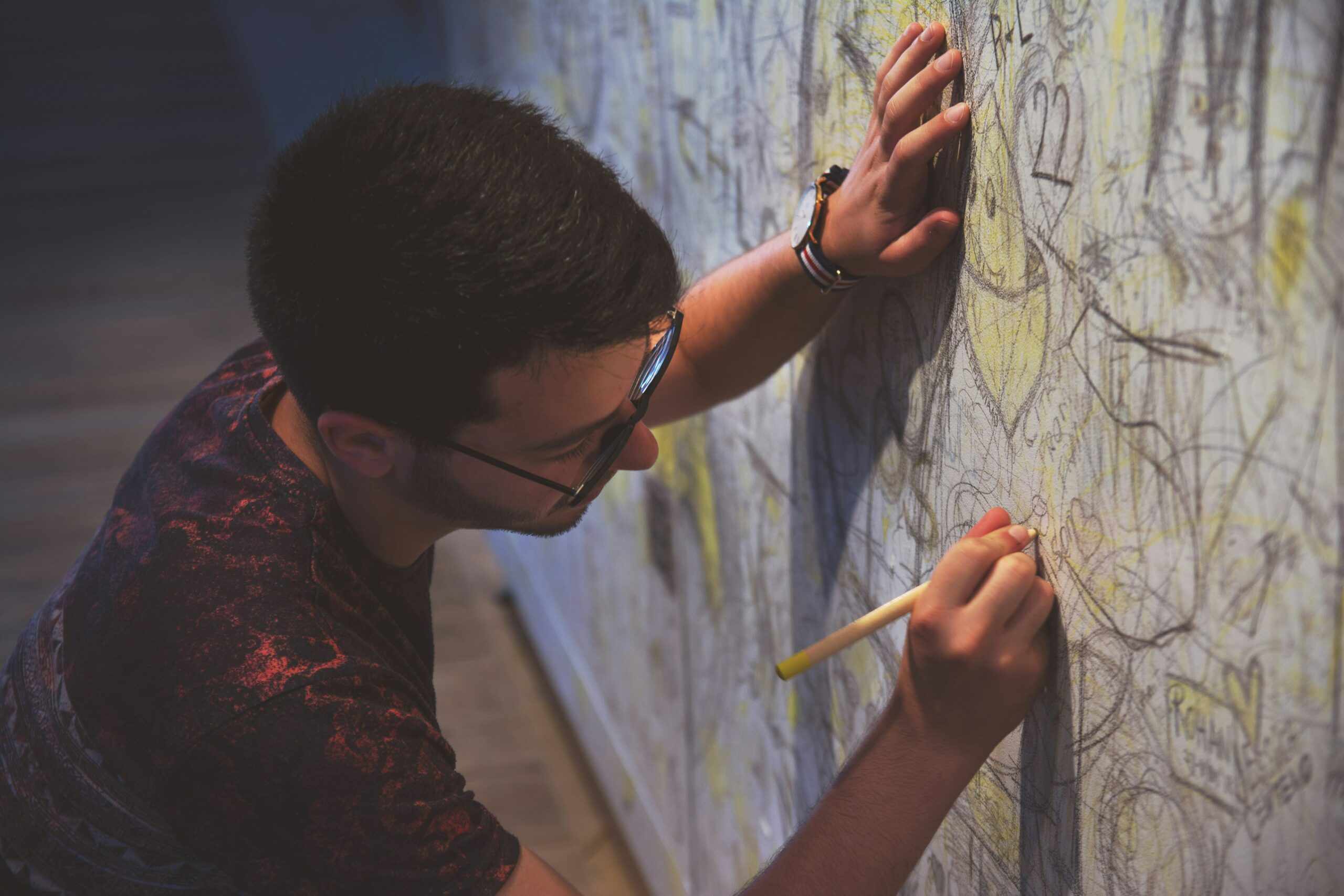 person holding a pen writing on a wall