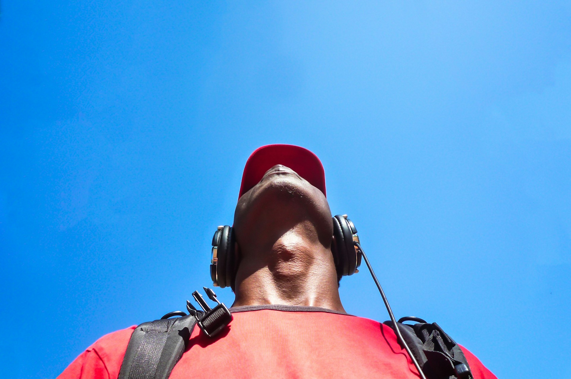 man looking to sky while uses a black headphone