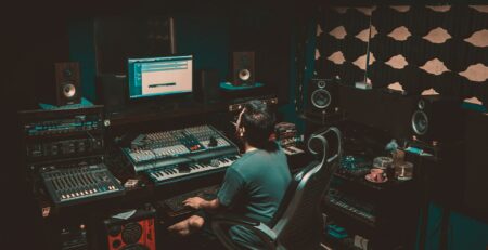 person sitting in front of a computer and a record studio