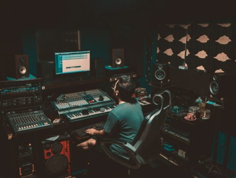 person sitting in front of a computer and a record studio