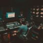 person sitting in front of a computer and a record studio