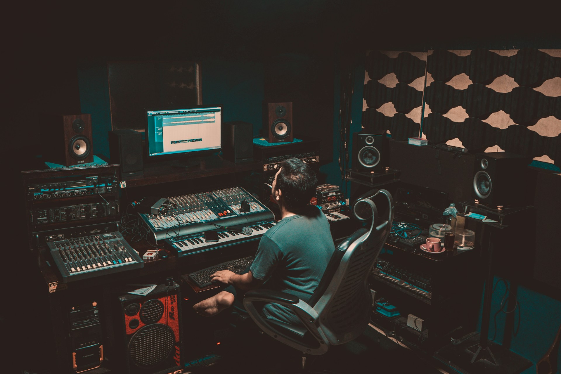 person sitting in front of a computer and a record studio