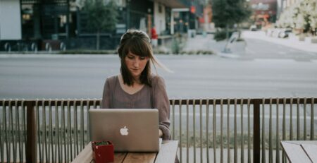 a woman sitting on a bench in front of a macbook