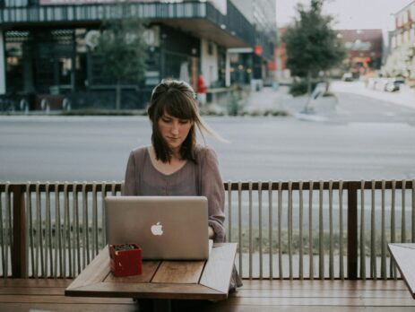 a woman sitting on a bench in front of a macbook