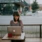 a woman sitting on a bench in front of a macbook