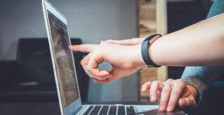 two hands pointing at a laptop